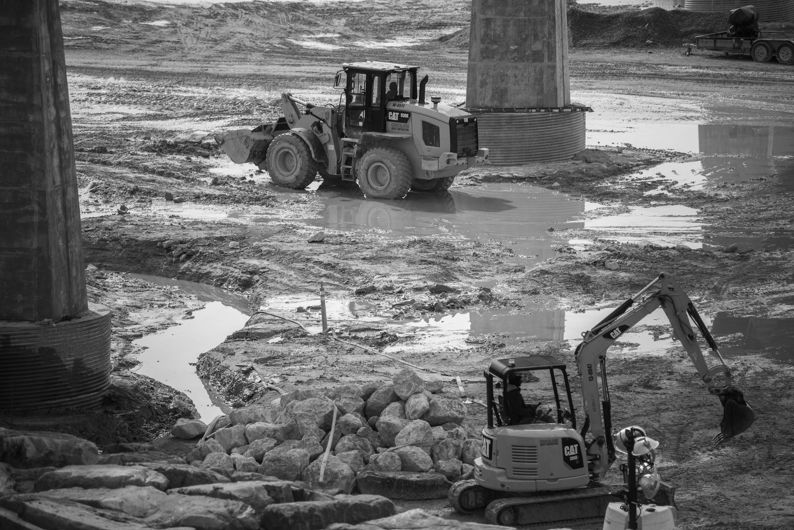 Cargador y excavadora entre columnas de una obra de infraestructura